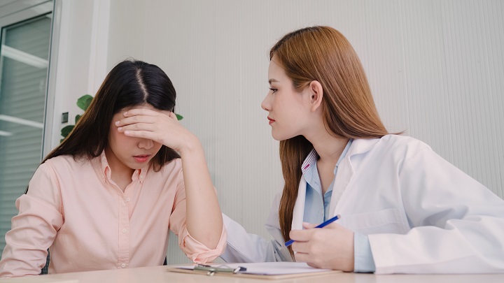 Psychiatrists talking to unhappy teenage patient in exam room.