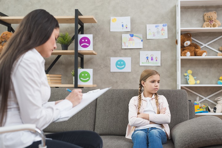 depressed girl sitting on sofa with female psychologist