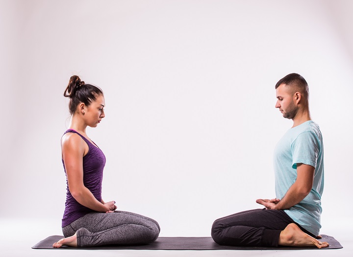 Young healthy couple in yoga position on white backgroundYoung healthy couple in yoga position on white background
